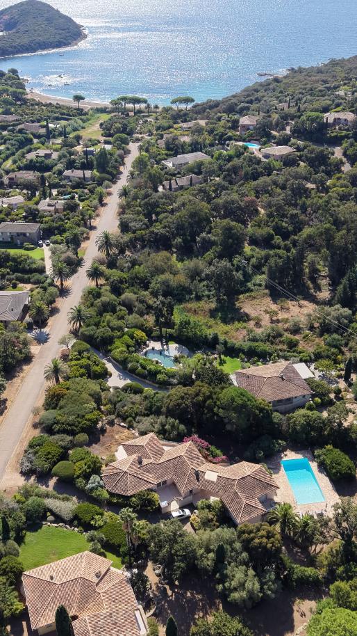 Vue aérienne du domaine : la villa et sa piscine au premier plan, la plage et la mer au fond